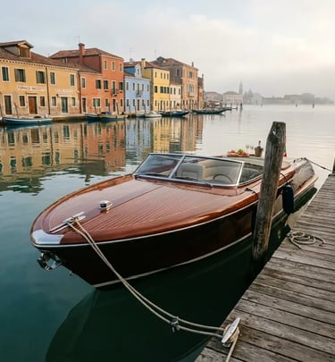 Riva Aquariva moored at wooden dock on Murano island with colorful buildings and morning fog