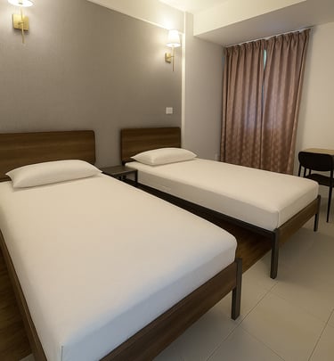 Modern hotel room featuring two twin beds with wooden frames and white linens under warm wall-mounted lamps.