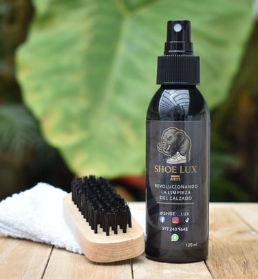 Shoe Lux sneaker cleaning kit with spray bottle, horsehair brush, and microfibre towel on wood.