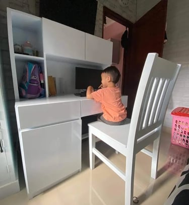 a young child sitting at a white desk made by DharmaJaya furniture Bali desk with a computer