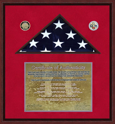 Framed American flag burial display with a certificate of authenticity and military service medals.