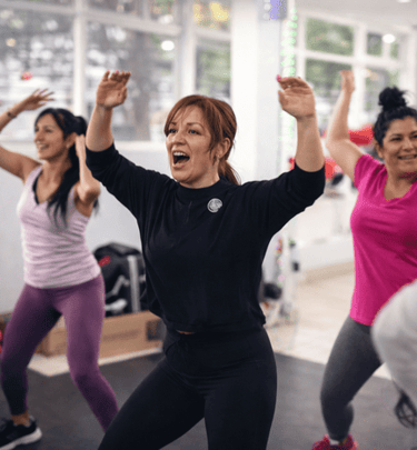  Grupo de mujeres sonriendo y bailando durante una animada clase de zumba fitness