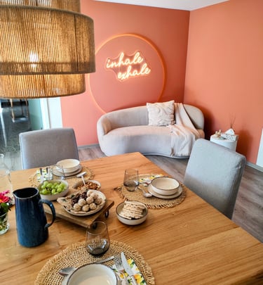 Ess-/Wohnzimmer in Retreathaus mit Couch im Hintergrund und Leckereien auf Esstisch im Vordergrund