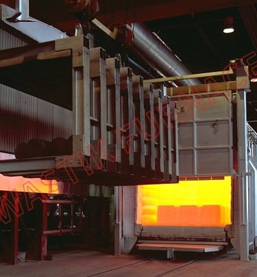 Industrial heat treatment furnace with open door showing glowing orange interior and loading mechanism.