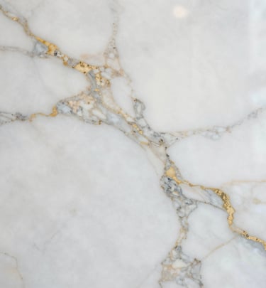 Stacks of granite slabs in varied earth tones, neatly arranged in a sunlit warehouse.