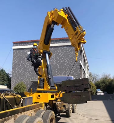 A large object being raised by a crane, specifically a 25 Ton Knuckle Loader Crane.