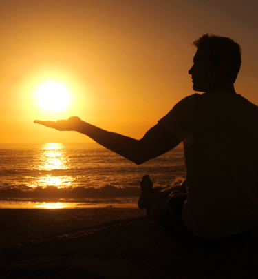 a man sitting on a beach holding a frisbee