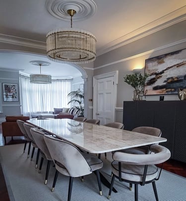 Sleek dining area with a marble table, velvet chairs, and modern chandeliers in an open-plan space