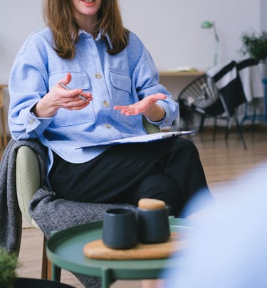 a woman in a blue shirt and black pants sitting in a chair