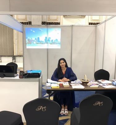 "Professional immigration consultant seated at an exhibition booth with a city skyline projection.