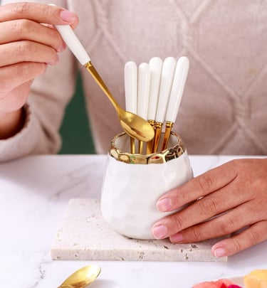 a woman's hands holding a gold spoon and spoons