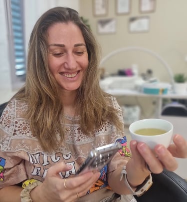 אישה יושבת בחדר טיפולים ונהנית מכוס תה חם תוך כדי מנוחה.