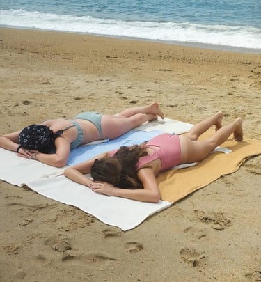 two women laying on a towel on a beach