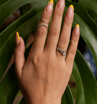 la main d'une femme avec des bagues et du vernis sur les ongles