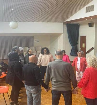 Church members standing in a circle holding hands in prayer during a small group meeting.
