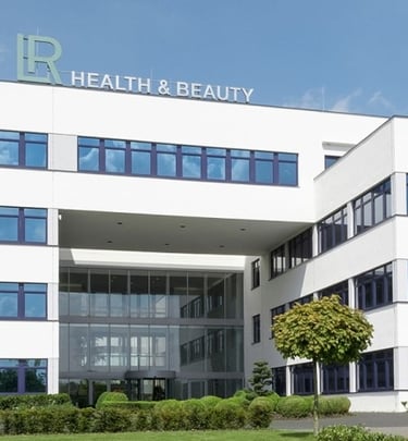 Modern LR Health and Beauty corporate office building with white facade and blue windows.