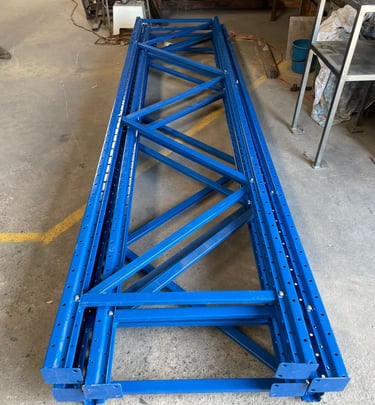Stack of assembled steel pallet racking uprights neatly arranged.