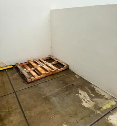 Empty concrete floor with a pallet next to a concrete wall