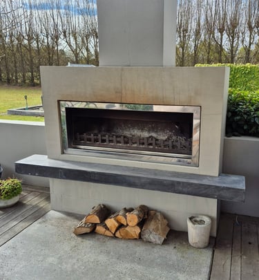 Modern outdoor fireplace with a concrete mantel and wood logs on a patio deck.