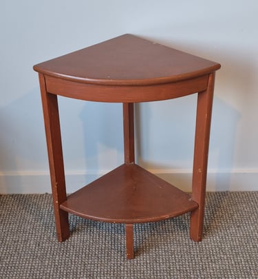 Vintage reddish-brown wooden corner side table with two tiers on a grey carpet.