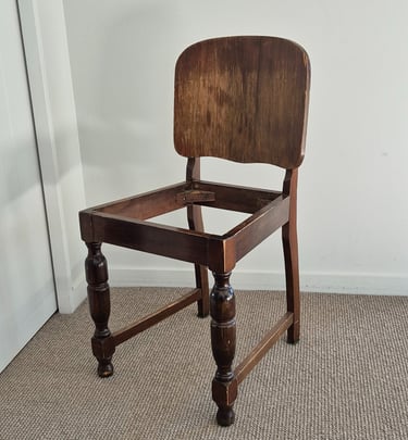 Vintage dark wood dining chair frame without a seat cushion, featuring turned legs and a solid backrest.