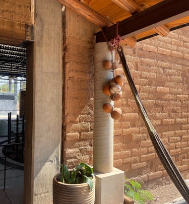 Rustic brick distillery interior with terracotta gourds hanging from a wooden beam.