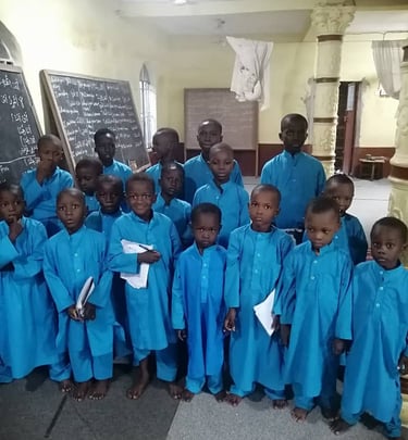 Smiling child holds Mushaf while studying Islam at Maakitheena school.