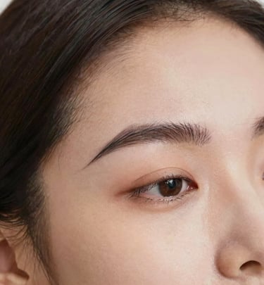Nila carefully threading a client's eyebrow with focused attention and care.