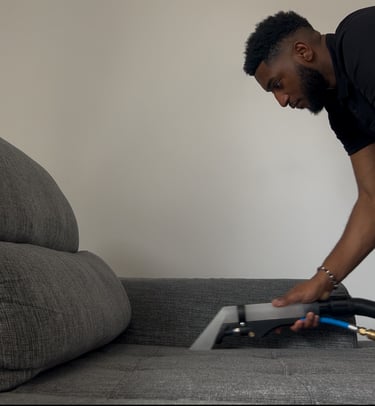 a man is cleaning a couch with a vacuum