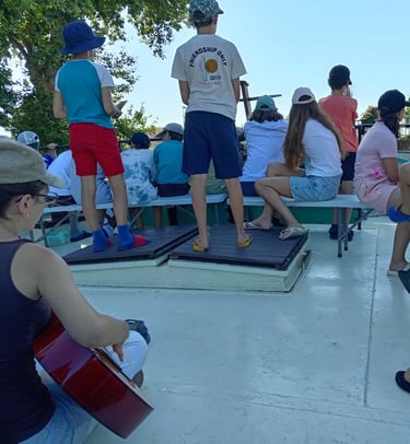 Colonie : animatrice à la guitare, jeunes réunis sur le pont.