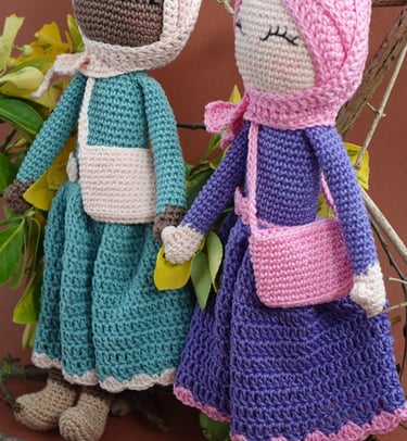 Two crochet dolls in a dress wearing the hijab are standing next to each other