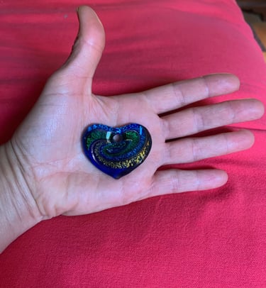 open hand with blue green 7 yellow glass heart on palm