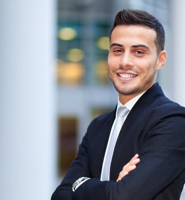 young man in suit smiling in front of an office building