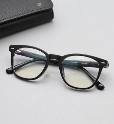 A close-up of stylish budget-friendly eyeglasses resting on a wooden table with soft natural light.