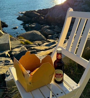 Fish and chips in takeaway boxes from Maritime Munchies enjoyed by the coast in Lofoten