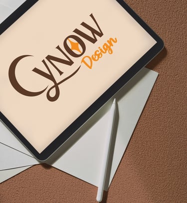 Une tablette graphique avec le logo "Cynow Design" est posée sur une pile de feuilles rigides