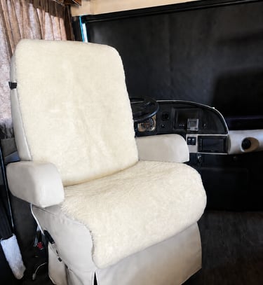 Cream sheepskin seat cover installed on a swivel captain chair in a luxury motorhome interior.