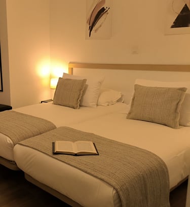 Habitación doble en Hotel Arias, Vigo, con escritorio y luz de mesilla encendida