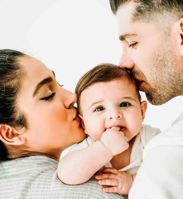 Parents kissing baby during family photoshoot – lifestyle family photography by Fred Art Studio