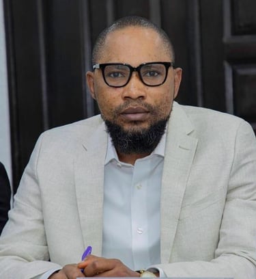 a man in a suit and glasses sitting at a table