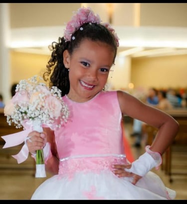 menina de 9 anos com vestido rosa e branco e um buque de fleres nas maos.