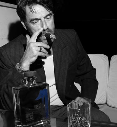 a man in a suit and tie is drinking a glass of uno tequila