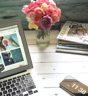 a laptop computer and a cell phone, roses and books on a table