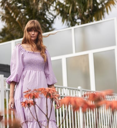 Fashion campaign photography - a woman in a purple dress standing in front of a fence