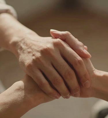A cinematic detail shot of two hands interlaced, shot with a shallow depth of field. Warm, sun-soaked lighting creates a sense of intimacy and authenticity. Incorporates subtle tones of #C06C4C in the warm glow.