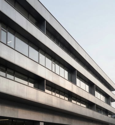 A wide perspective shot of the contemporary facade of Academia Acto. Sharp architectural lines made of pale silver gray materials and deep charcoal metal frames. Editorial style, clean composition against a neutral sky.