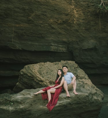 Intimate couple sitting on rock formation during sunset at Pantai Nyanyi Bali.