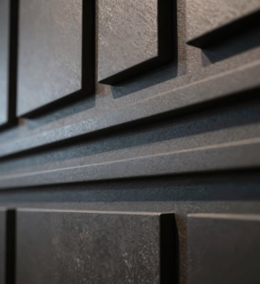 Extreme close-up photography of architectural 3D textures, featuring matte dark charcoal and muted steel grey surfaces. The lighting is elegant and directional, mimicking a North American / US modern art gallery display.