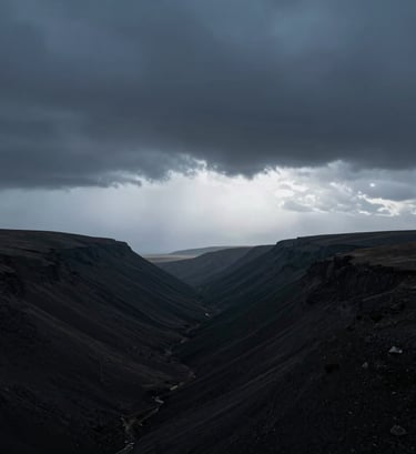 A vertical minimalist landscape photograph showing a vast, dark valley under a storm cloud. A soft glow of light blue-grey breaks through the horizon. Clean, modern aesthetic with a focus on scale and atmospheric perspective. International / Western countryside.