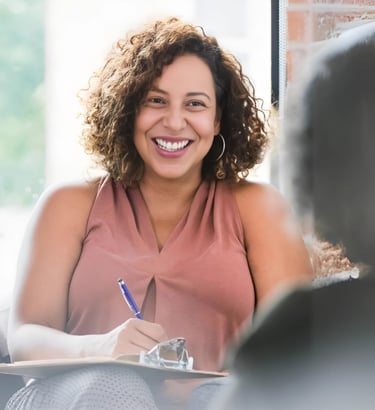a woman sitting on a couch with a pen and a notebook